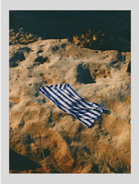 a blue and white striped towel laying on a rocky beach